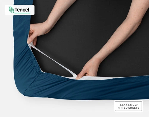 Underside of our BeechBliss TENCEL™ Modal Fitted Sheet in Seaport Blue to show its stay snug elastics being pulled by two hands.