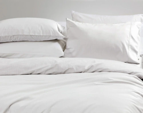 Closer view of our Bamboo Cotton Duvet Cover in White draped over a bed with coordinating pillows.