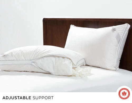 Two of our Adjust-A-Pillows on a plain white bed, one zipped open its foam revealed while the other is sealed.