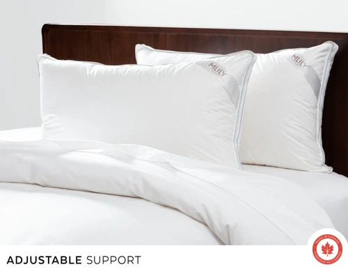 Two Adjust-A-Pillows resting upright at the head of an all-white bed.