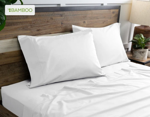 Two of our Bamboo Cotton Pillowcases in White resting on a wooden bed with coordinating sheets.