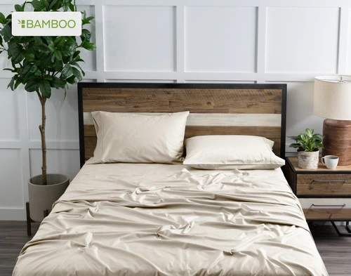 Top view of our Bamboo Cotton Sheet Set in Driftwood Beige dressed over a wooden bed in a white plant-filled bedroom.