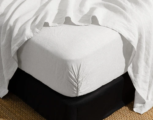 Corner of our Signature European Linen Fitted Sheet in White fit snugly around a mattress.