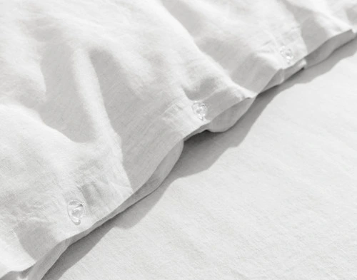 Close-up on our Signature European Linen Duvet Cover in White to show its classic button enclosure.