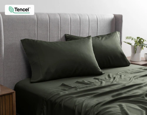 Angled view of two BeechBliss TENCEL™ Modal Pillowcases in Rainforest Green resting on a twin bed dressed in matching sheets.