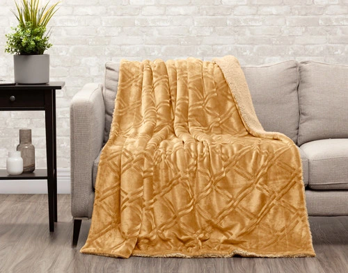 Angled view of the reverse of Diamond Etched Throw in Gold draped over a chair.