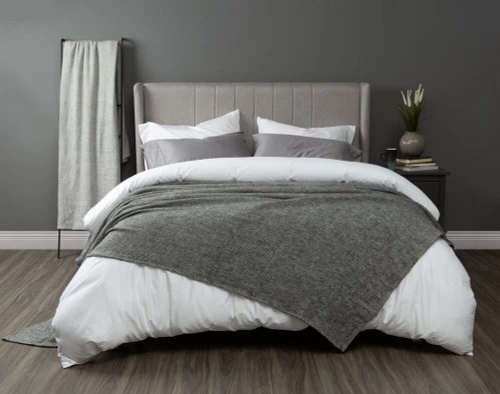 Our Grey Wool Blend Blanket in Lismore draped over an elegant modern bed.