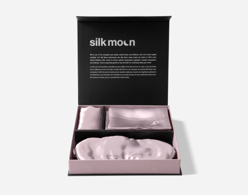 Our Mulberry Silk Gift Set in Lavender from the front with its in its open packaging, showing its pillowcase, delicates bag, and eye mask.