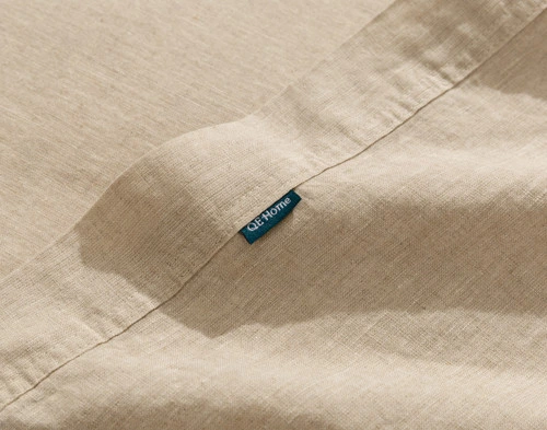 Close-up on the hemmed edge and small QE Home tag on the border of our Signature European Linen Flat Sheet in Natural.