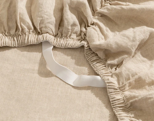 Close-up on a loose Signature European Linen Fitted Sheet in Natural to show its Stay Snug elastic band and soft linen fabric.