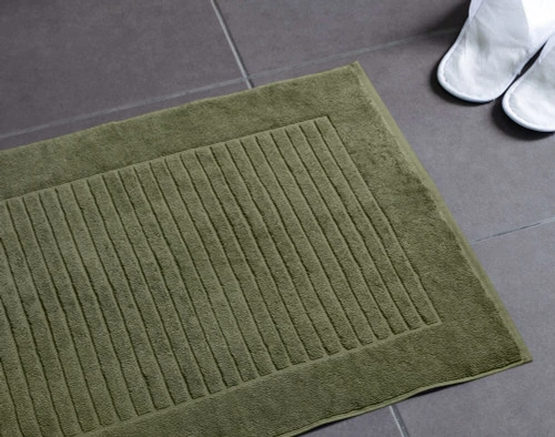 Our Modal Cotton Green Bath Mat laying on a dark grey bathroom floor.