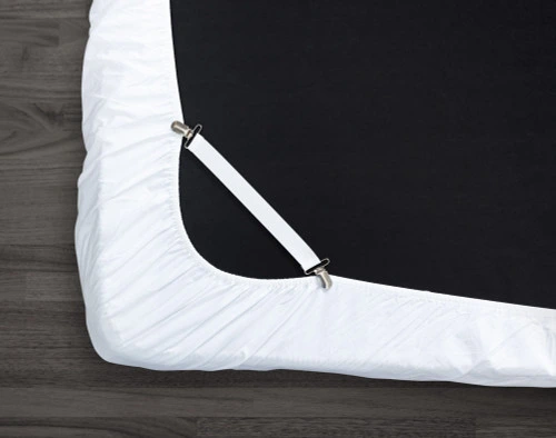 Sheet strap attached to corner of an upside-down mattress, clipping the bottom-left corner to keep it snug over top.