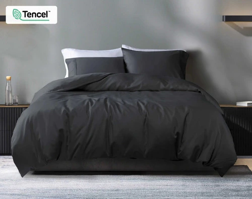 Front view of our Eucalyptus Luxe TENCEL™ Lyocell Duvet Cover in Black Pearl dressed over a queen bed with grey sheets in a white modern bedroom.