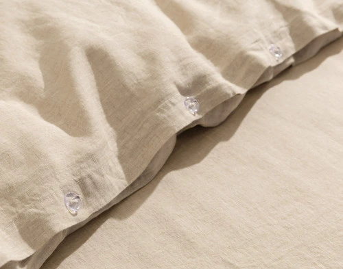 Close-up on our Signature European Linen Duvet Cover in Natural to show its classic button enclosure.