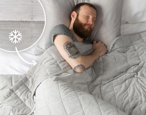 Top view of a man sleeping under our All-Seasons Weighted Blanket with the cooling side over him.