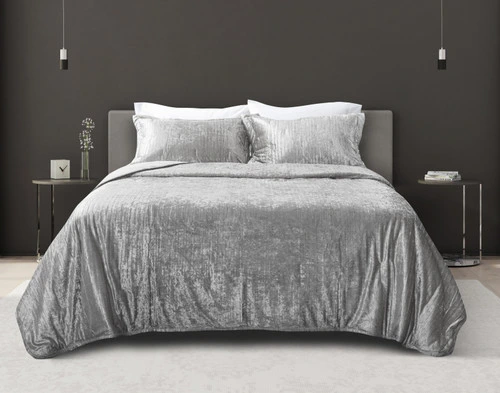 Front view of our Avalon Quilt Set in Silver dressed over a bed in a dark brown bedroom with wood panel flooring.