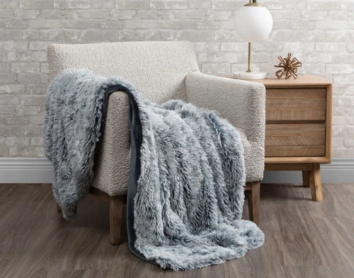 Our Frosted Shaggy Throw in Thundercloud Grey draped over a chair in a white room.