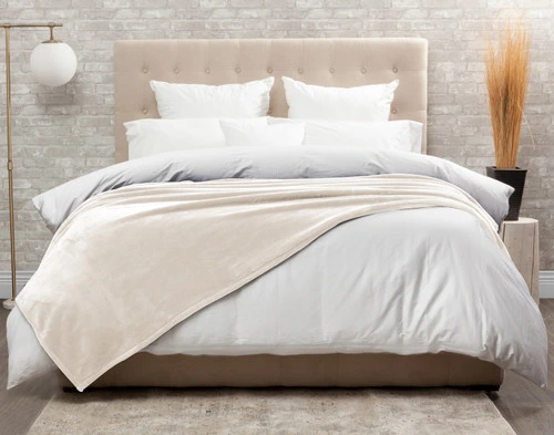 Front view of our Cashmere Touch Fleece Blanket in Cloud White draped over a tidy white bed.