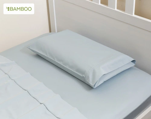 Angled view of our Small Bamboo Cotton Pillowcase in Sky Blue in a children's white bed.