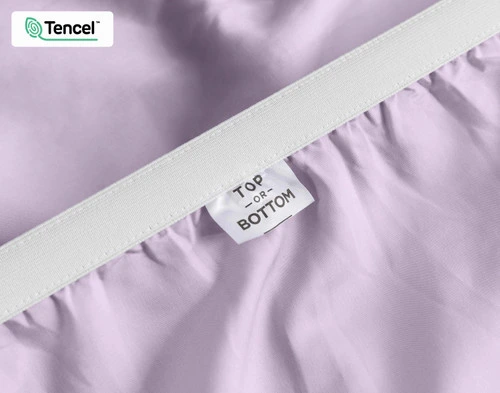 Close-up on the stretched elastic edge and tag stating "Top / Bottom" on our Eucalyptus Luxe TENCEL™ Lyocell Fitted Sheet in Lilac.