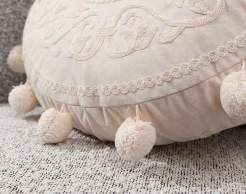 Close-up on the decorative sphere tassels on the side of our Embroidered Round Cushion.