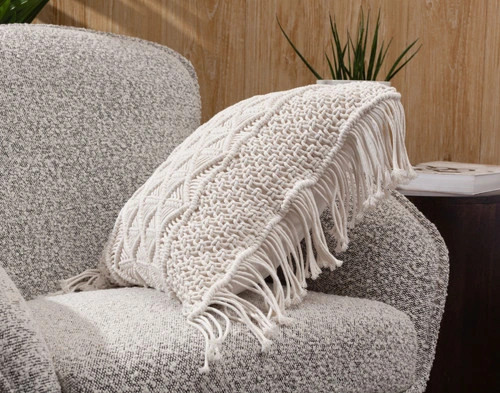 Side view of our Macramé Square Cushion Cover leaning on the arm of a grey chair.