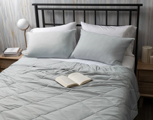 Top view of our Cool Touch Blanket in Grey Stripe spread over a queen bed with coordinating pillowcases and a book resting over it.