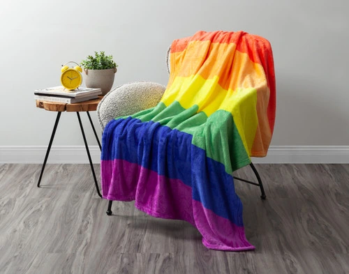 Our traditional Pride Rainbow Fleece Throw draped over a chair in a white living room.