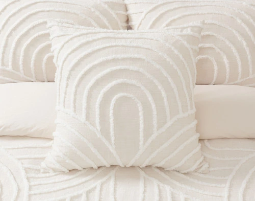 Front view of our Sonrisa Euro Sham sitting in front of multiple coordinating pillows on a white bed.