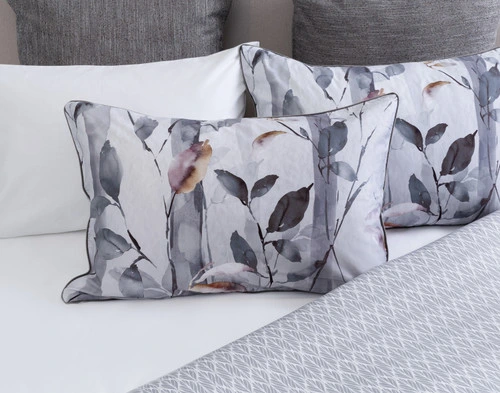 Front view of our Tamarak Pillow Sham leaning against coordinating pillows on a half-dressed white bed.