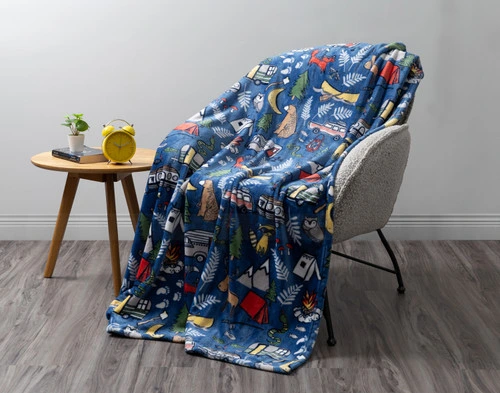 Front view of our Adventure Camp Kids' Fleece Throw draped over a small modern chair against a solid grey background.