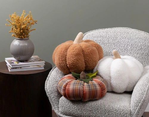 Our White, Copper, and Plaid pumpkin cushions sitting in a chair together.