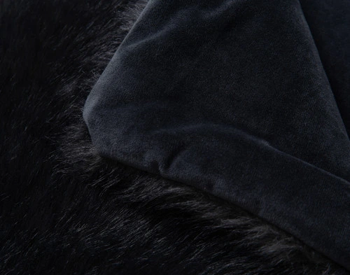 Close-up on the folded smooth reverse on the corner of our Polar Fur Throw in Onyx.