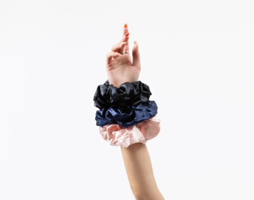 Picture of a feminine hand pointing upward with all three of our Mulberry Silk Oversized Scrunchie colours together on their wrist.