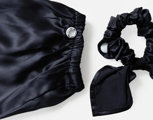 Close-up on our Mulberry Silk Bun Cover in Black to show its cover and scrunchie side-by-side.