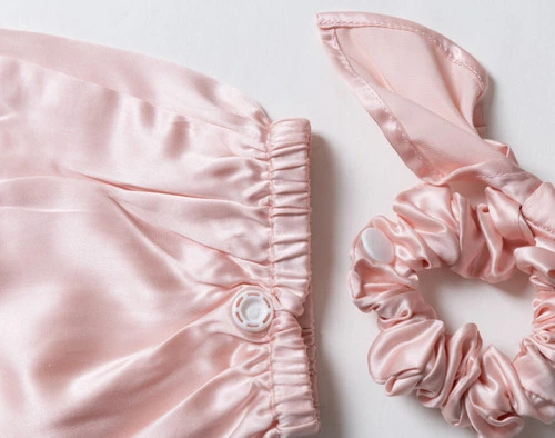 Close-up on our Mulberry Silk Bun Cover in Blush to show its cover and scrunchie side-by-side.