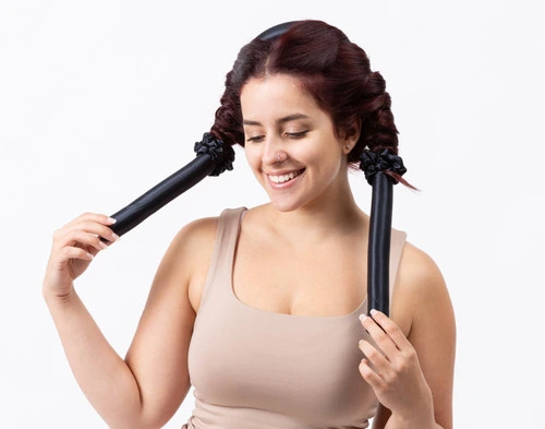 Angled view of a woman wearing our Silk Wrapped Heatless Curler Set in Black in a white room.