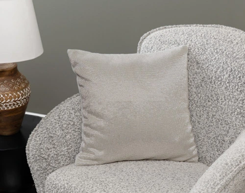 Angled view of our Beaded Square Cushion Cover in Silver sitting in a small grey armchair in a traditional living room.