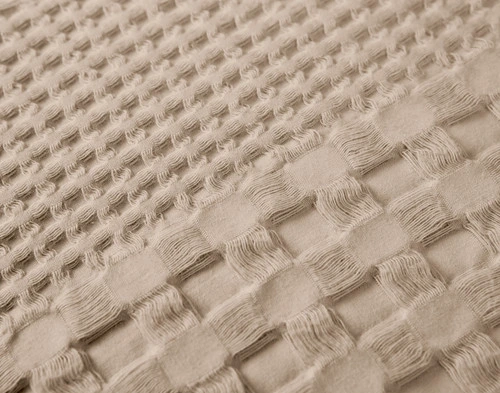 Angled view of two Waffle Cotton Euro Shams in Driftstone sitting against the headboard of a light beige bed.