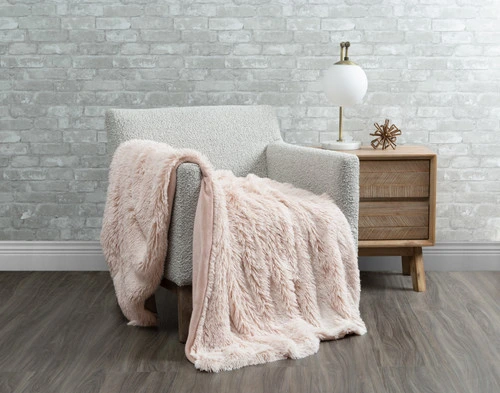 Our Frosted Shaggy Throw in Woodrose draped over a chair in a white room.