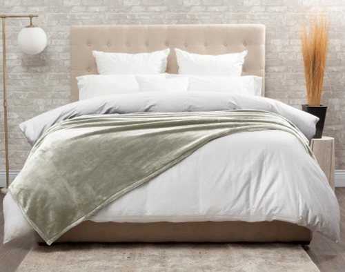 Front view of our Cashmere Touch Fleece Blanket in Mushroom draped over a tidy white bed.