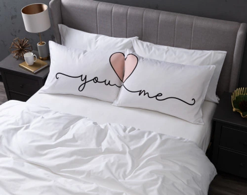 Aerial view of our You Heart Me Pillow Talk Pillowcases dressed over queen pillows in a large white bed.