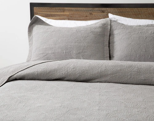 Angled view of our Elden Cotton Quilt Set to show its textured surface and matching pillow shams side-by-side.