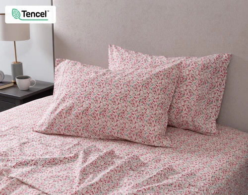 View of two pillowcases and our Carefree Cotton Caress Sheet Set leaning against the headboard of a beige bed.