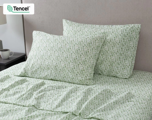 View of two pillowcases and our Carefree Cotton Caress Sheet Set leaning against the headboard of a beige bed.