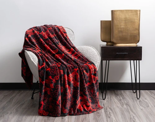 Angled view of our Lucky Dragon Throw in Red Luck draped over a modern grey armchair in a white room.