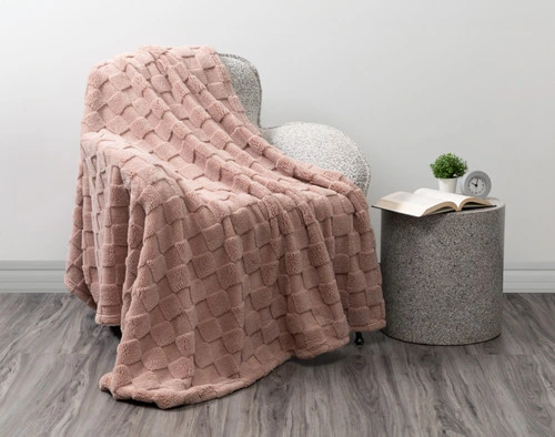 Angled view of our Checkered Teddy Throw in Frosted Berry draped over a modern grey armchair in a white room.