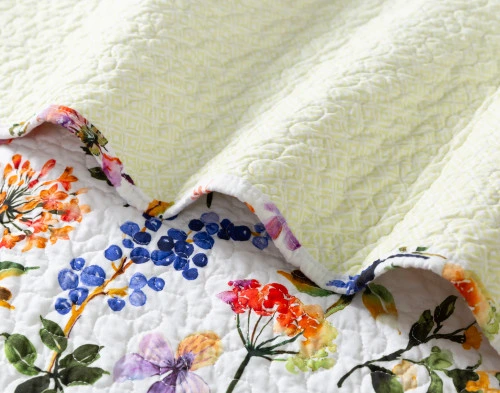 Close-up on a ruffled edge of our Maxine Floral Cotton Quilt Set to show its floral surface and solid backing side-by-side.