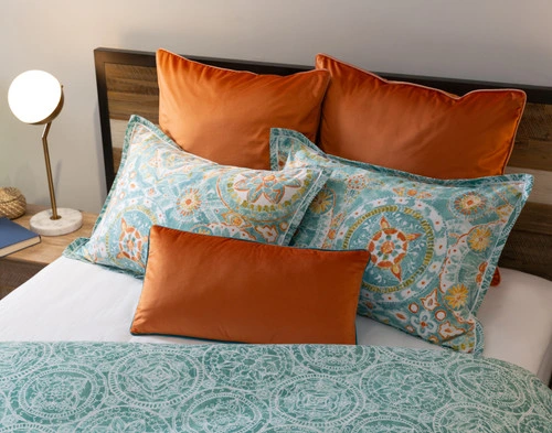 Angled view of the pillow shams, euro shams, and boudoir pillow cover for our Fiji collection sitting on a half-dressed white bed.