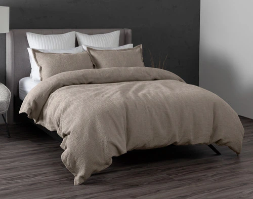 Angled view of our Brava Duvet Cover dressed over a plain queen bed in a dark grey modern bedroom.